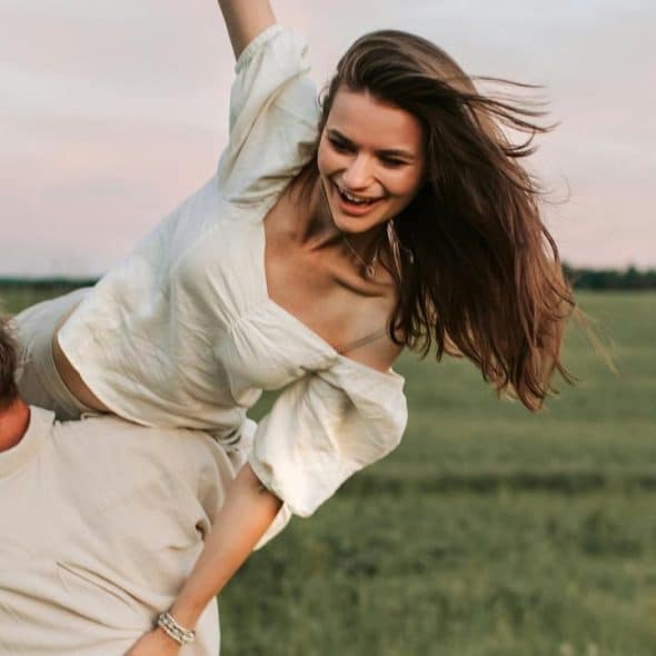 A man carrying a woman on his back in a field.