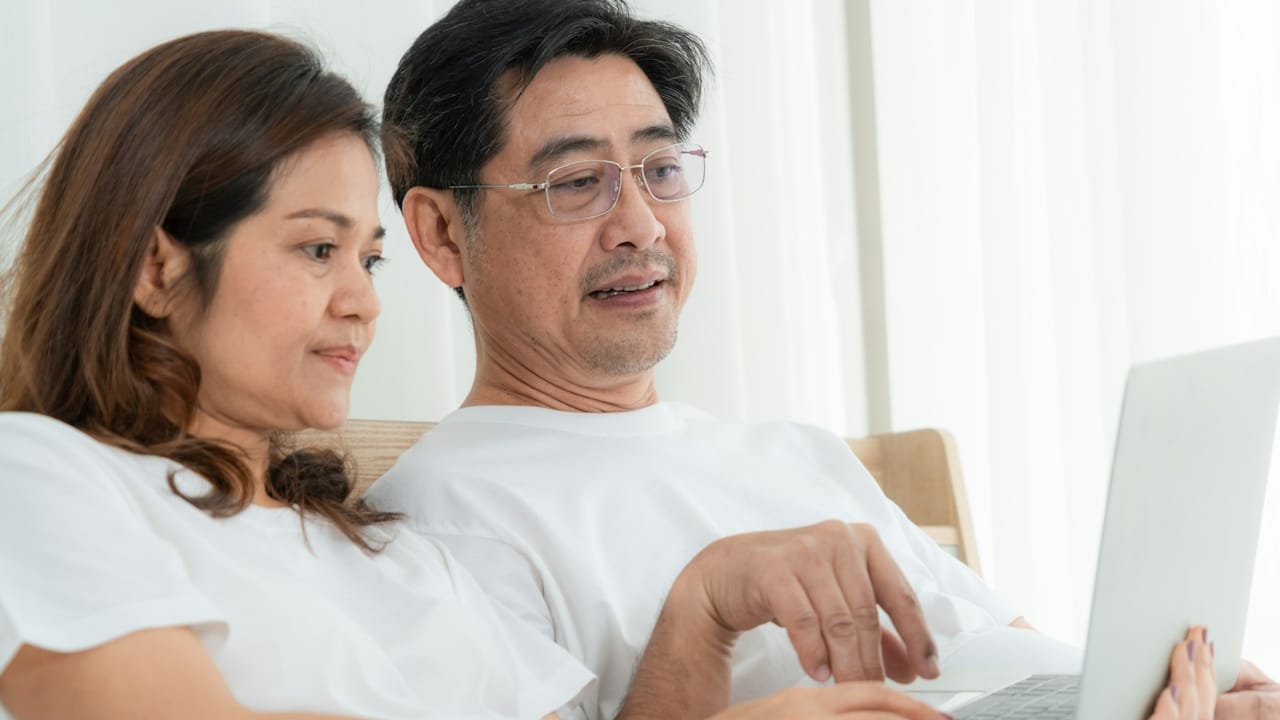 A mature couple working on laptop while sitting together.