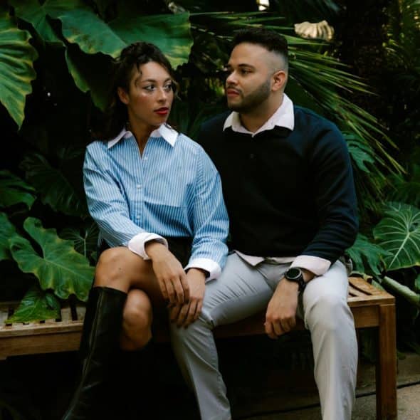 A couple sitting on a bench in a lush botanical garden