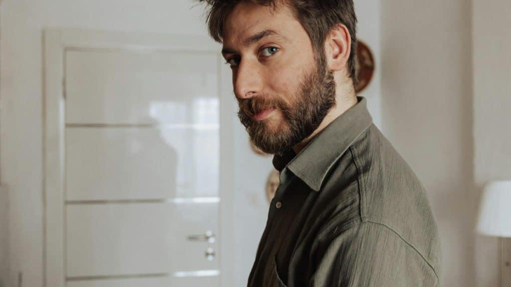 A bearded man looking over his shoulder indoors.The argument started about dirty dishes. Now you're questioning his entire existence as a functional human being. "You never think about anyone but yourself!" Cool. So we've officially abandoned the original topic and moved into full-blown psychological warfare.