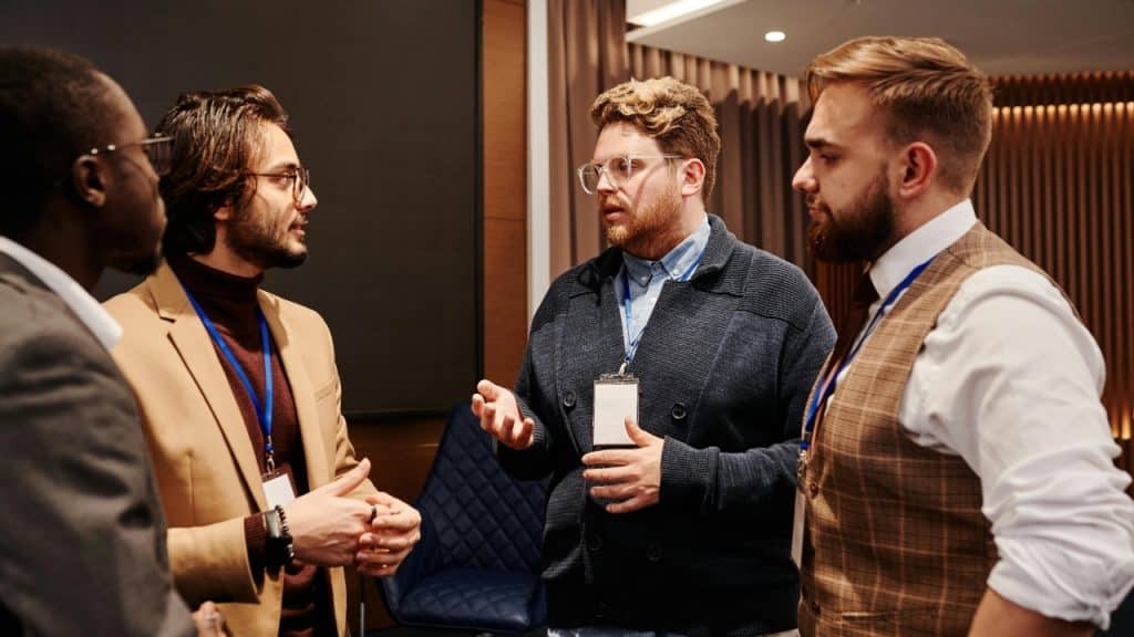 Four men in professional attire stand in a circle and engage in a conversation.