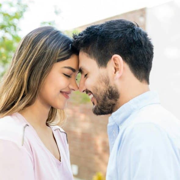 Side view of a romantic couple touching foreheads during a date.
