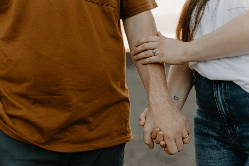 A close up of a couple holding their hands.