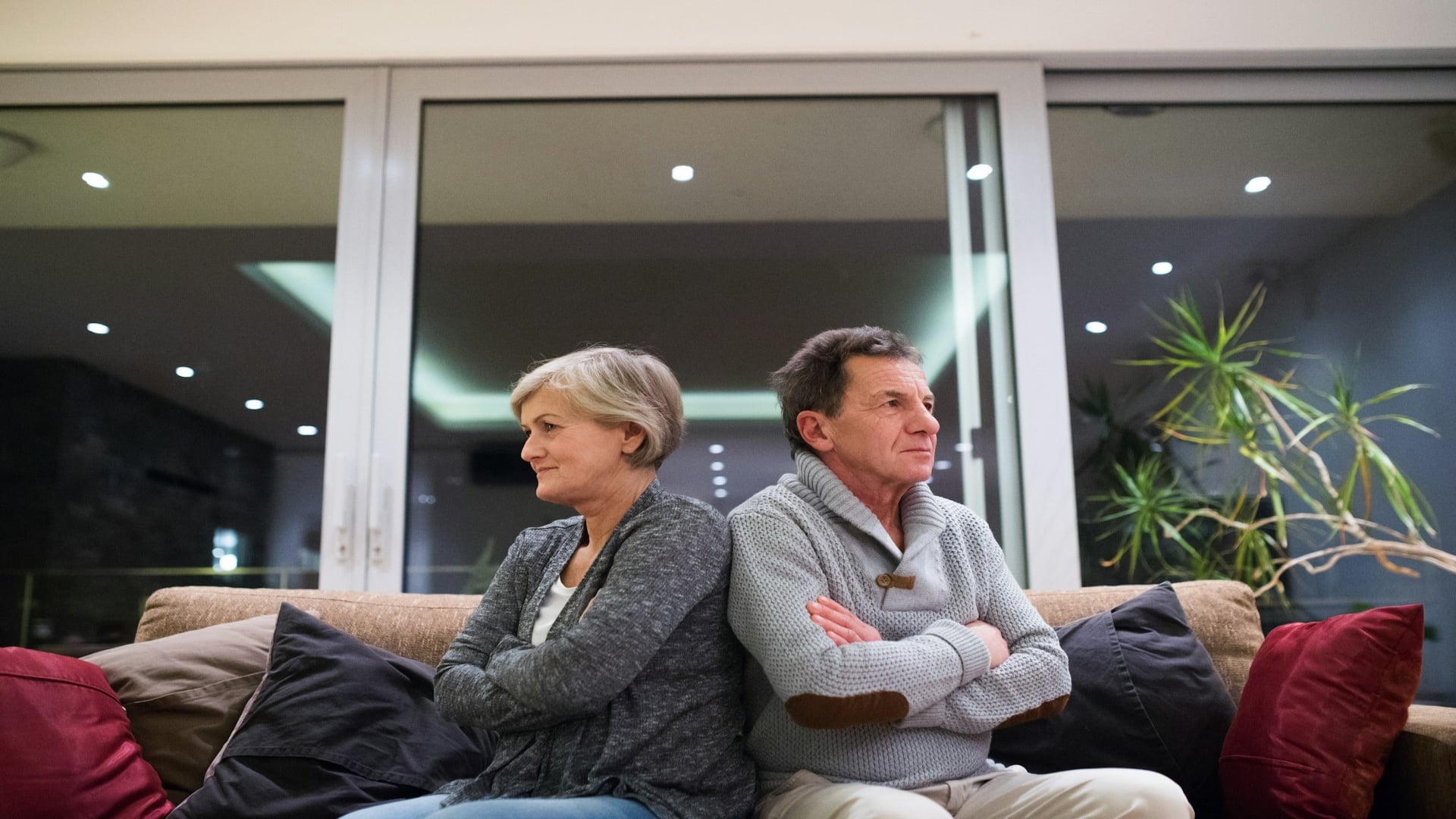 couple sitting apart on couch looking serious