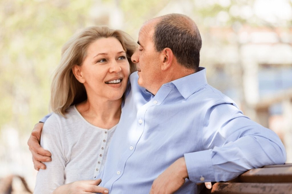 Happy middle age couple hugging on a bench