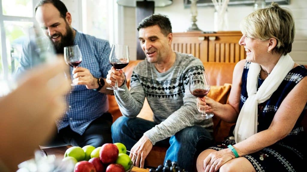 A group of people sitting together and enjoying glasses of red wine.