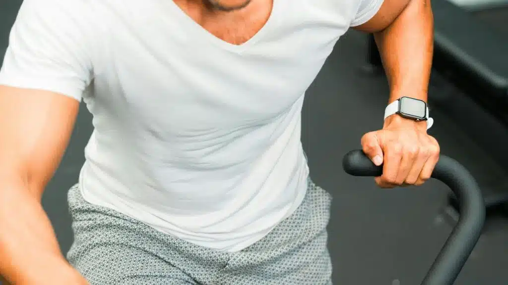 A man in a white shirt using an exercise bike.