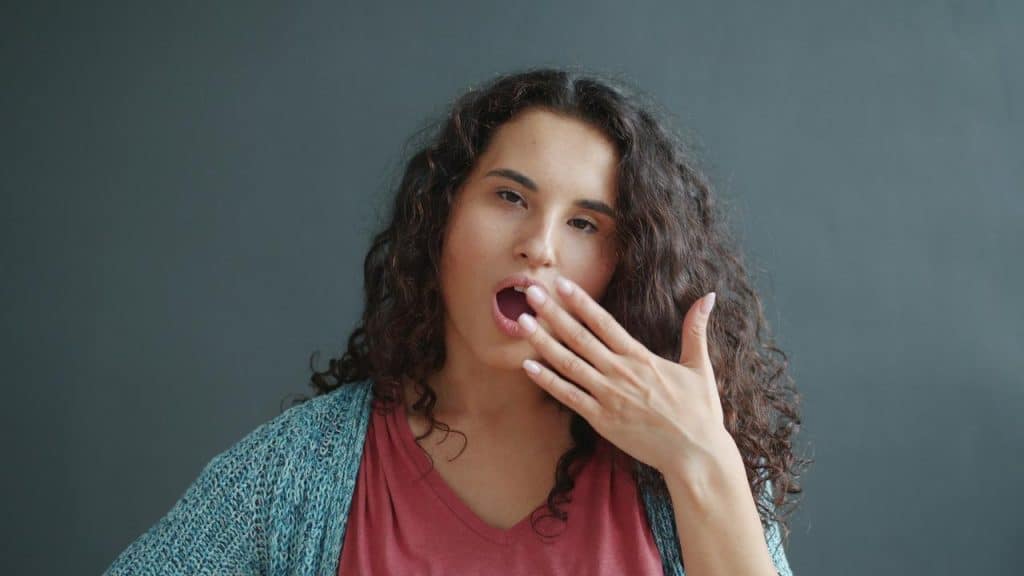 A woman yawning with her hand covering her mouth.