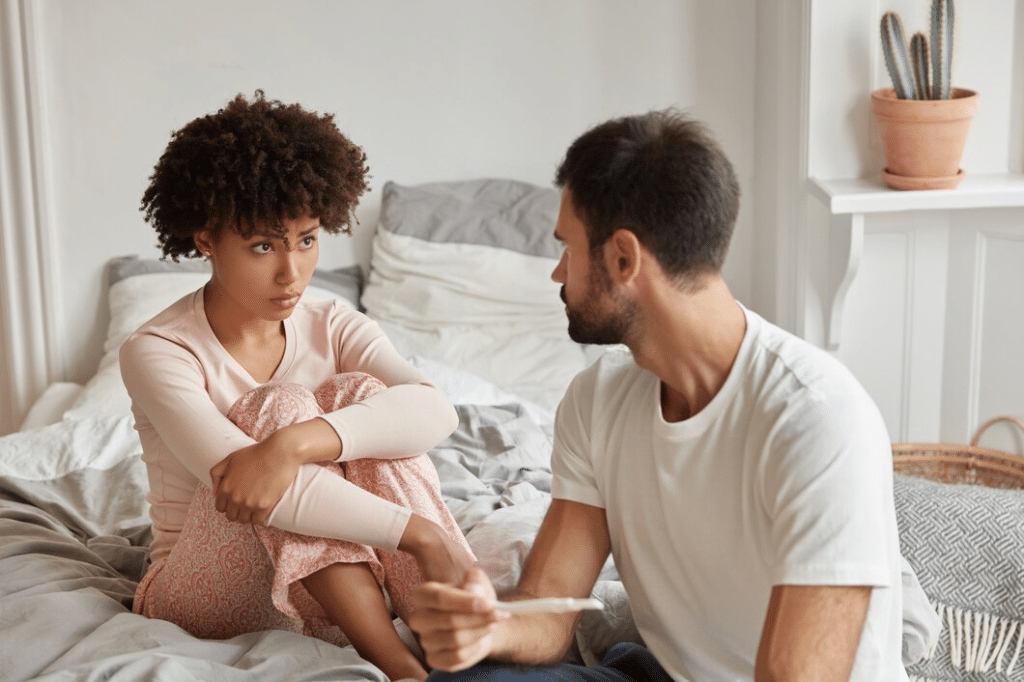 Unhappy couple sitting on bed looking at each other