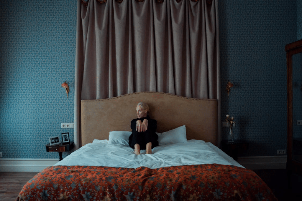 Mature woman sitting on bed, looking sad