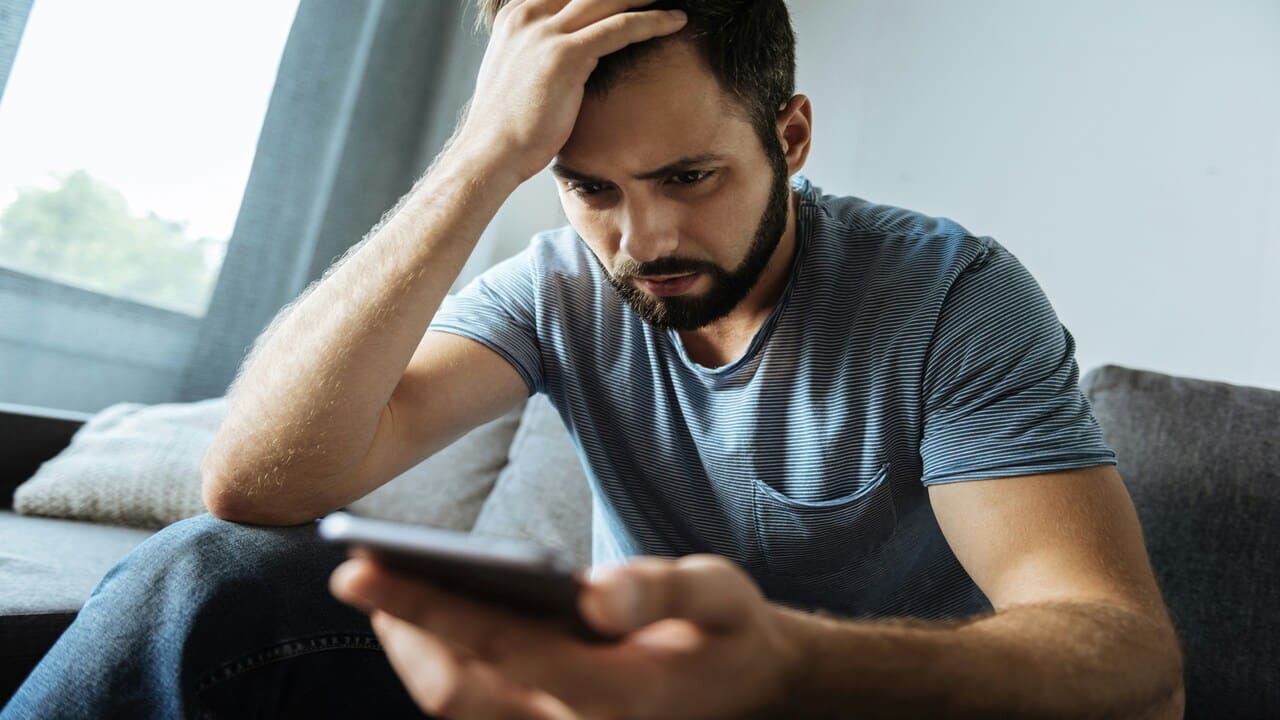A man looking sadly at his phone