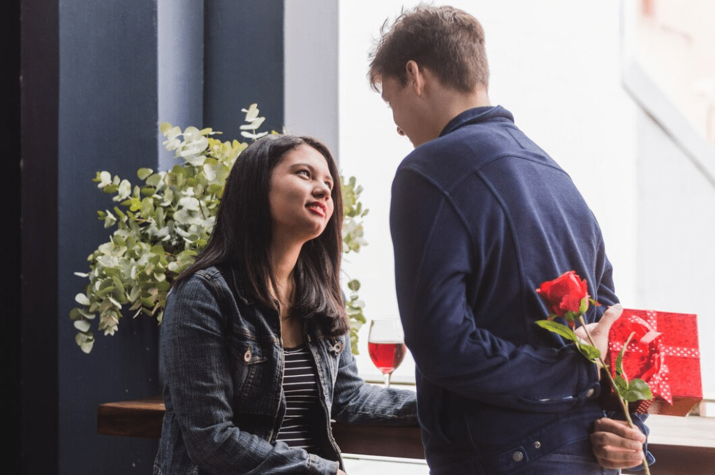 Man hiding rose behind back to woman