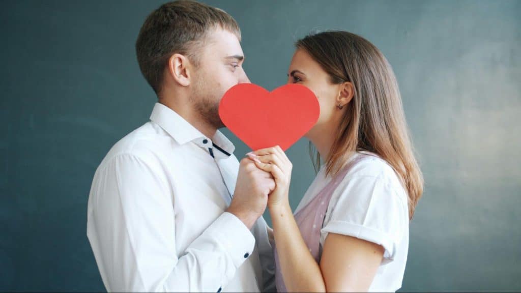 A man and woman holding a heart shaped paper