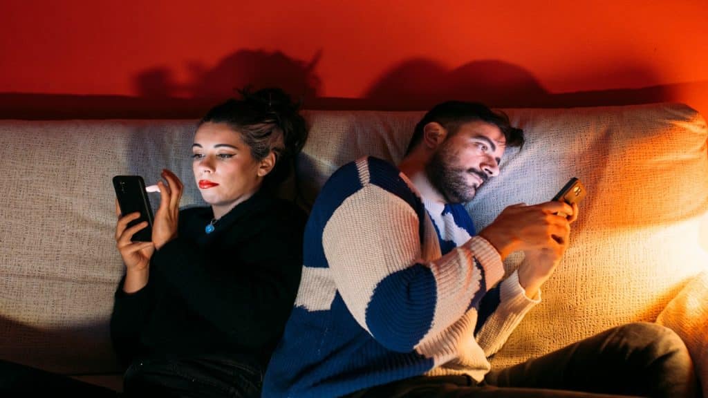 couple sitting together but distracted by phones