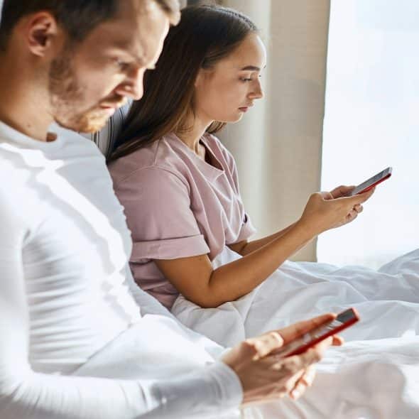 man and woman texting while sitting apart
