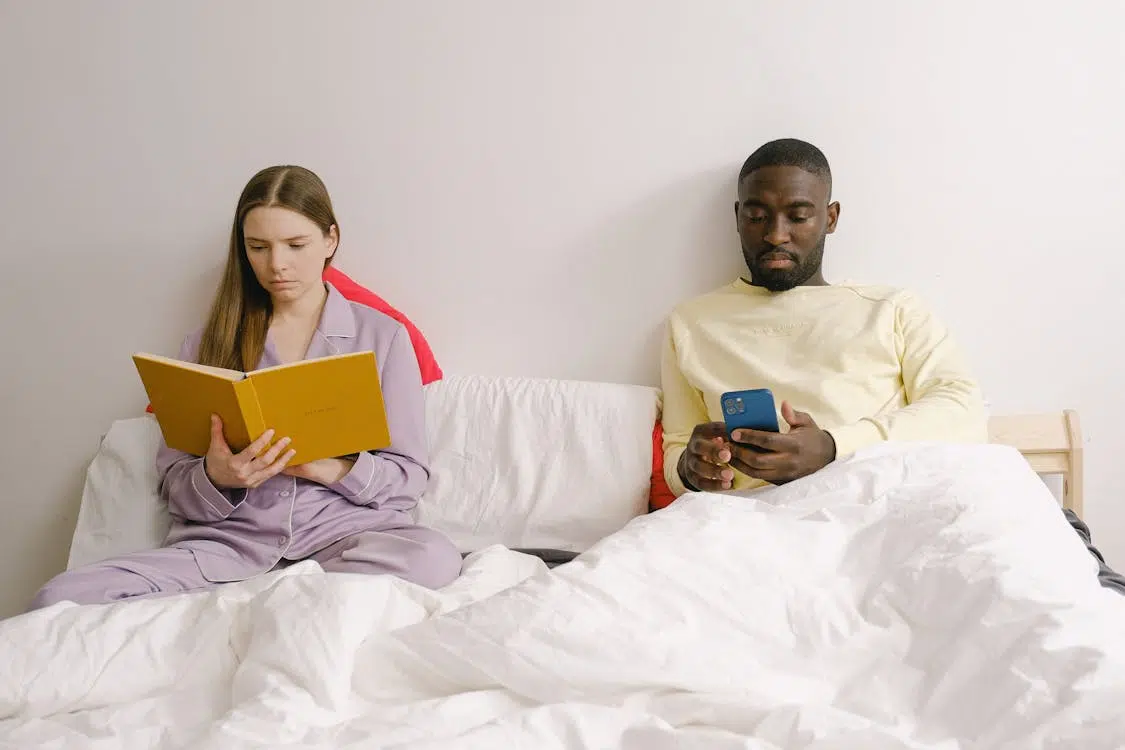 Couple sitting apart on bed