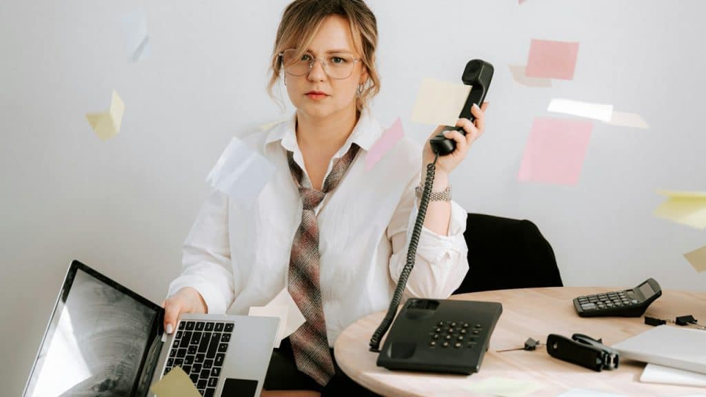 Overwhelmed worker surrounded by floating notes.