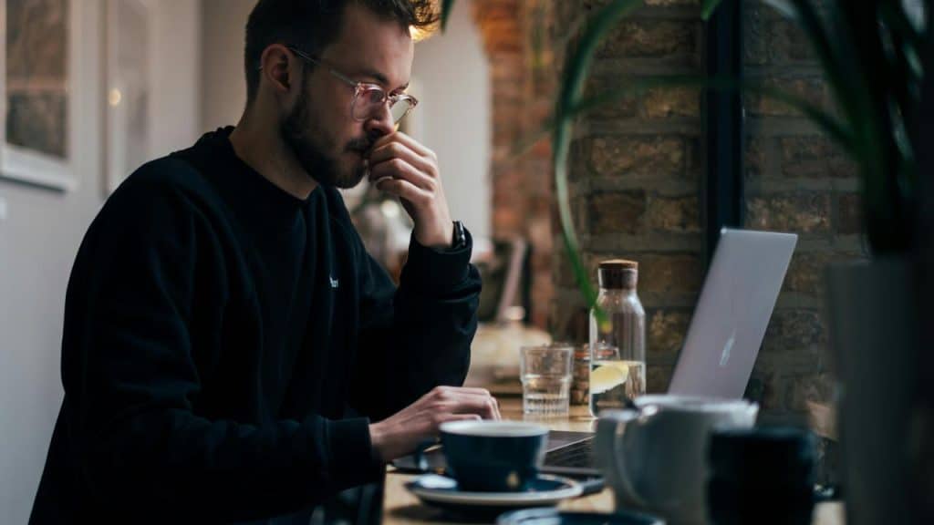 A man working on a laptop at a café table.
