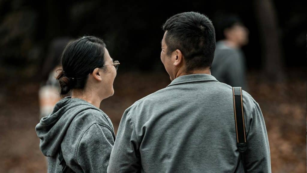 A couple standing with their backs to the camera and smiling at each other.