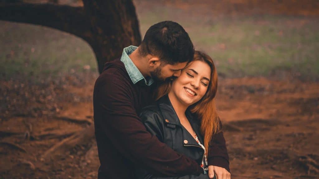 A couple hugging outdoors in a park.