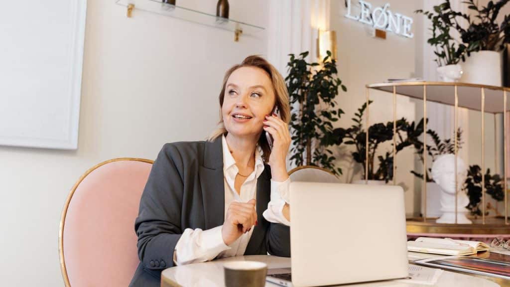 A businesswoman sitting at a desk with a laptop while talking on her phone.