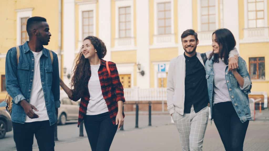 A group of friends walking down a street and smiling.