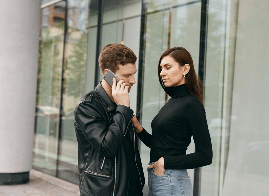 A man busy talking with somebody on the phone while woman waiting for him