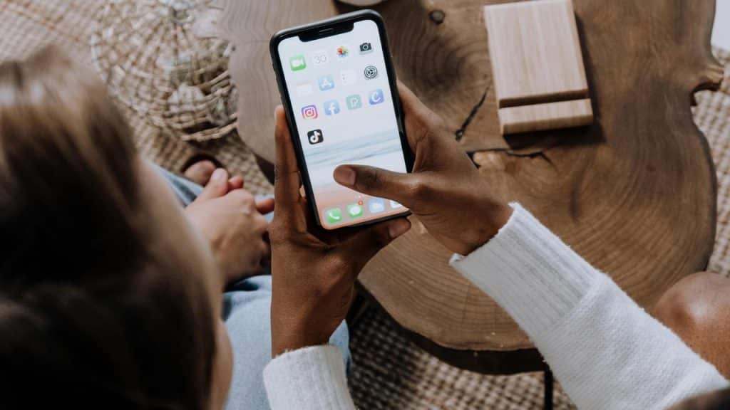 A person holding a smartphone and scrolling through apps.