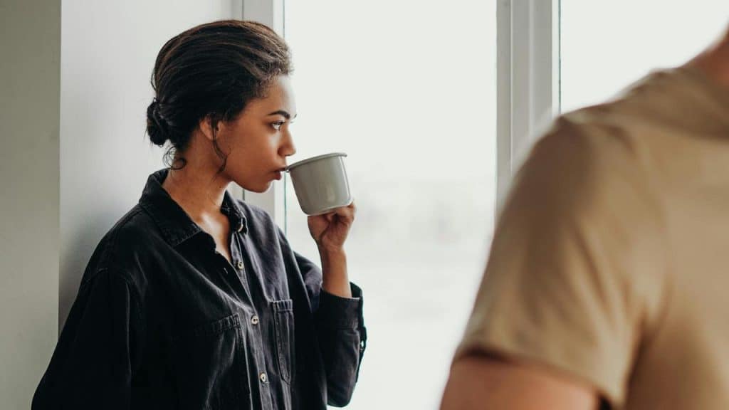 A woman in a dark shirt drinking from a mug 