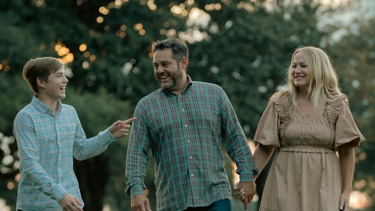 A man and a woman walking through a park.