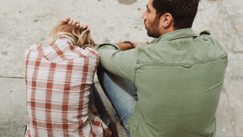 A couple sitting on a sidewalk
