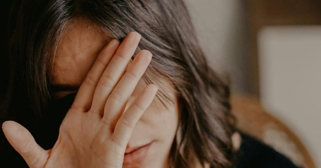 A person covering part of their face with a hand in a close-up view.