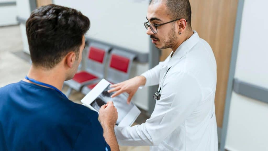 A doctor discussing an X-ray with a patient in a hospital hallway.