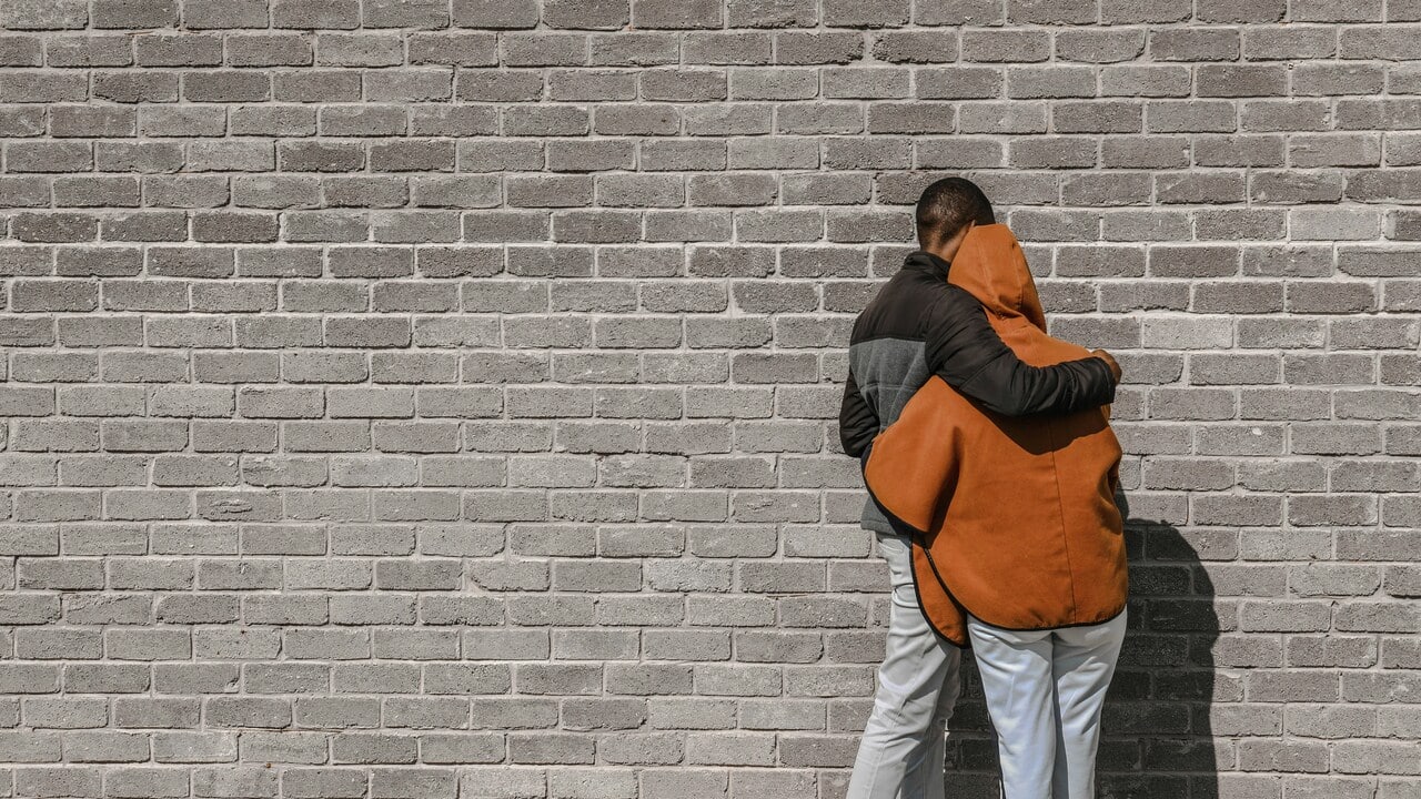 A couple hugging in front of a wall