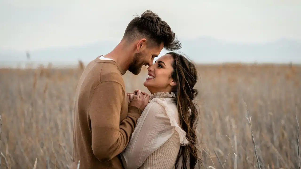 Couple looks at each other lovingly in a field.
