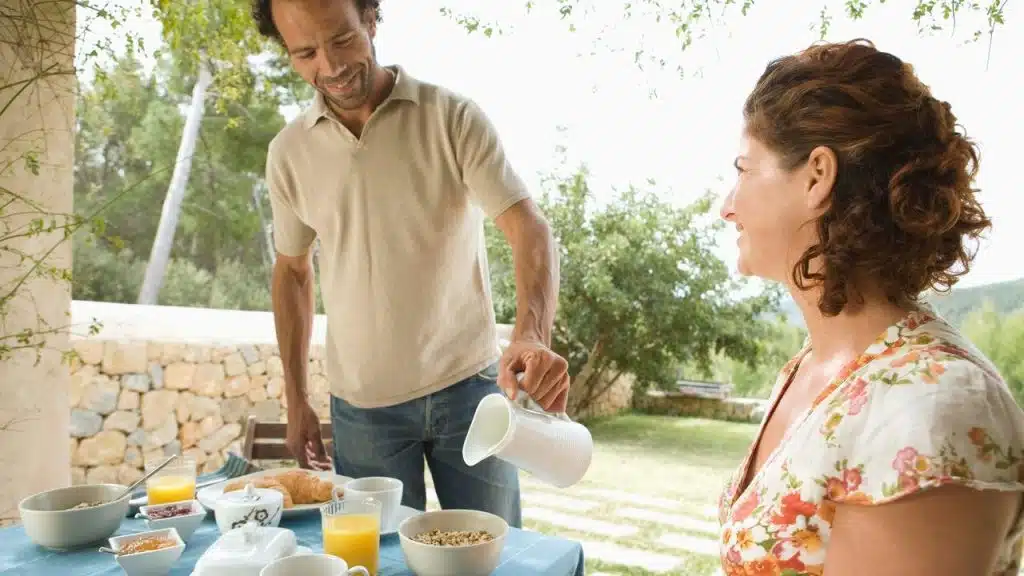 A man pouring coffee while sharing breakfast with a woman