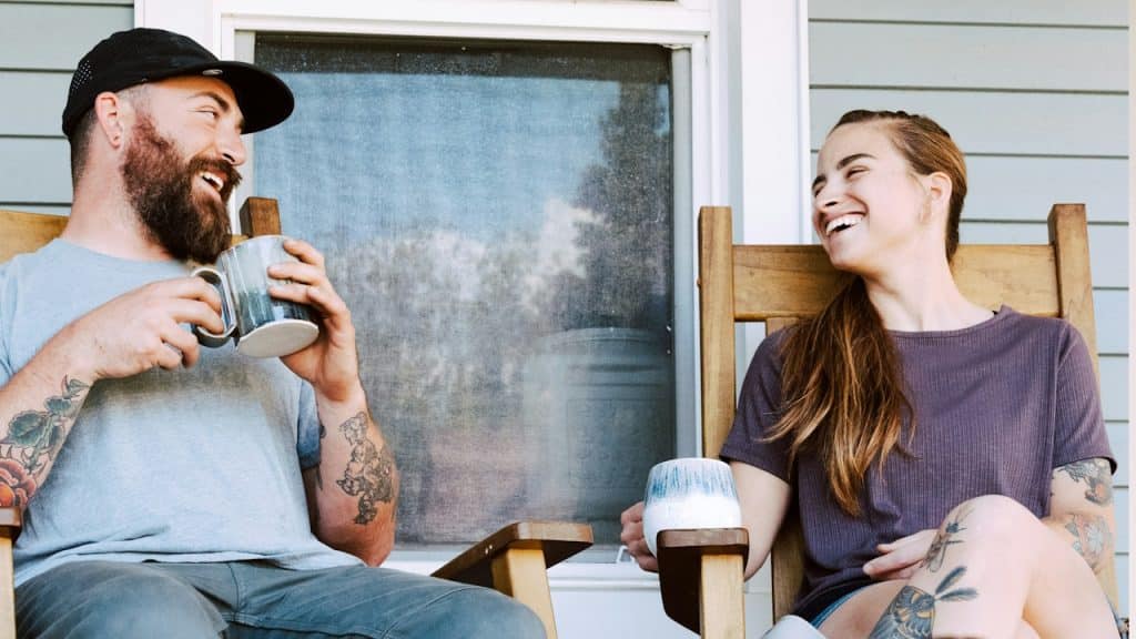 A man and a woman having coffee while sitting on a terrace together in the evening.