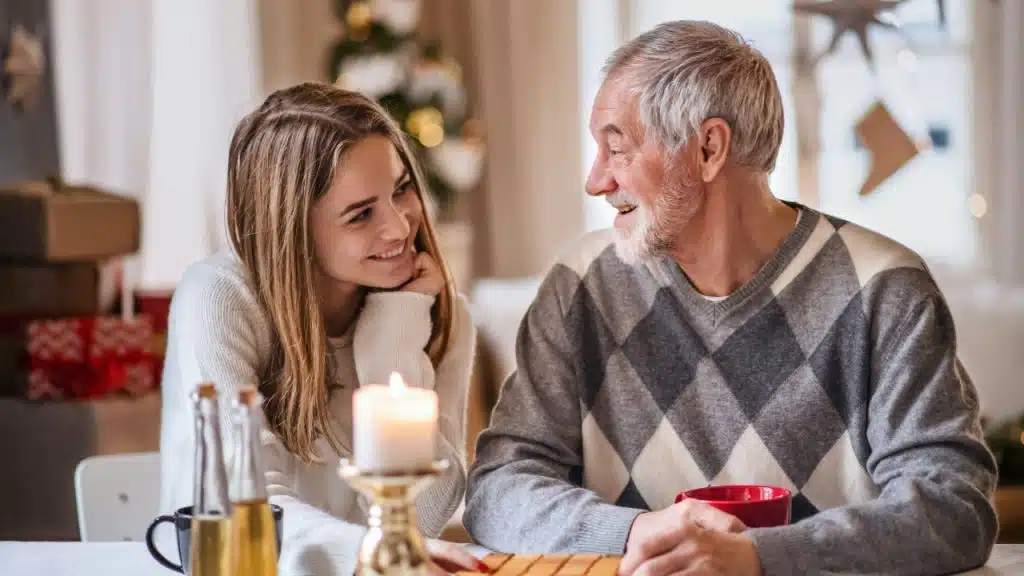 A young woman and an older man sit at a table with a lit candle.