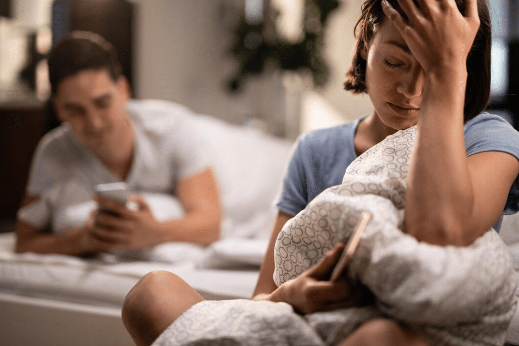 Young sad woman with a headache sitting in the bedroom
