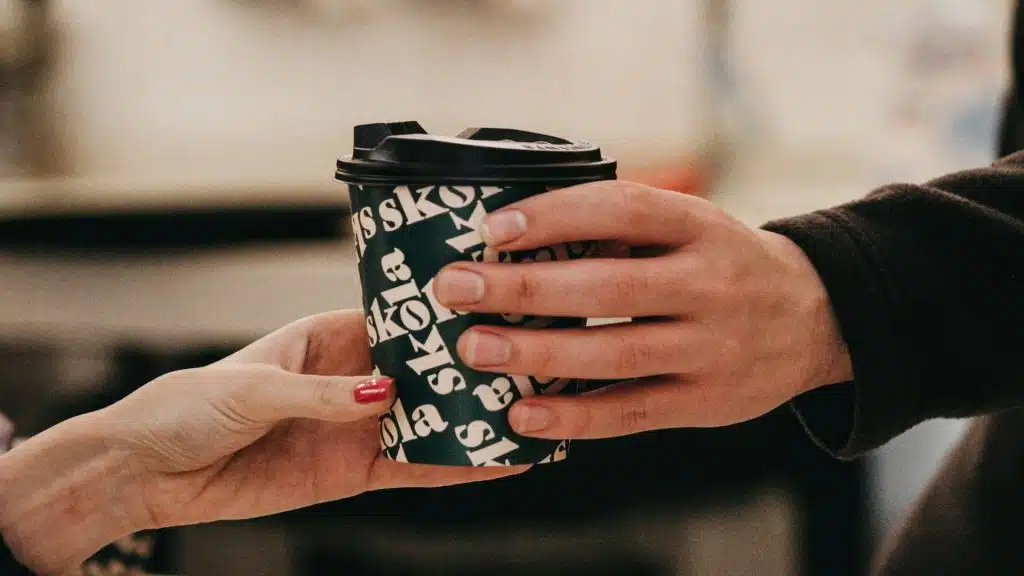 man handing coffee to partner