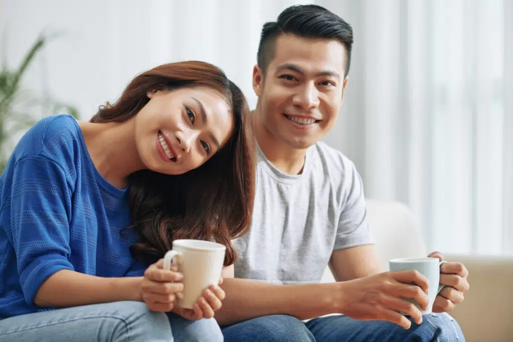 Happy young couple having coffee sitting on couch