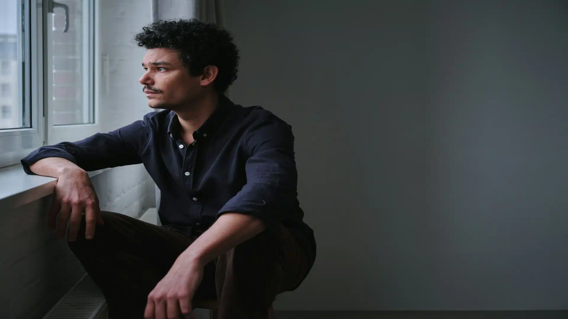 man looking thoughtful by window