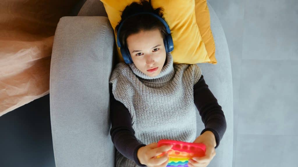 A woman with headphones plays with a pop-it toy.