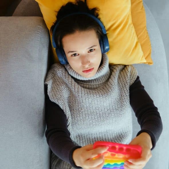 A woman with headphones plays with a pop-it toy.