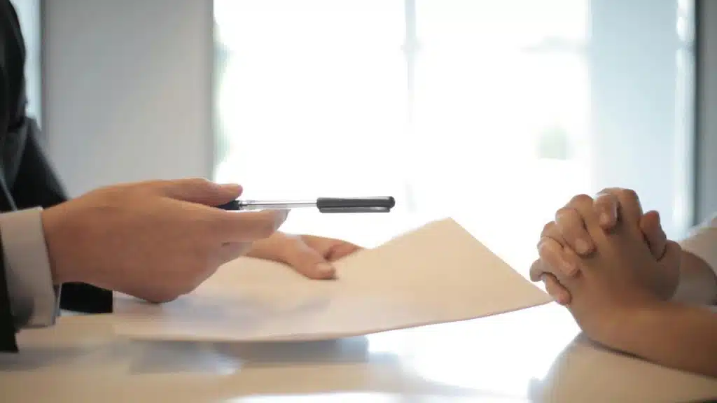 A hand giving someone a contract for signing