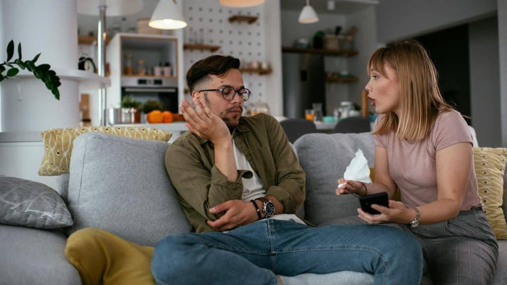 A woman yelling at her boyfriend while they are sitting together at home.