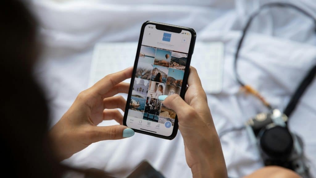 A person holds a smartphone showing a grid of various travel and architecture photos.