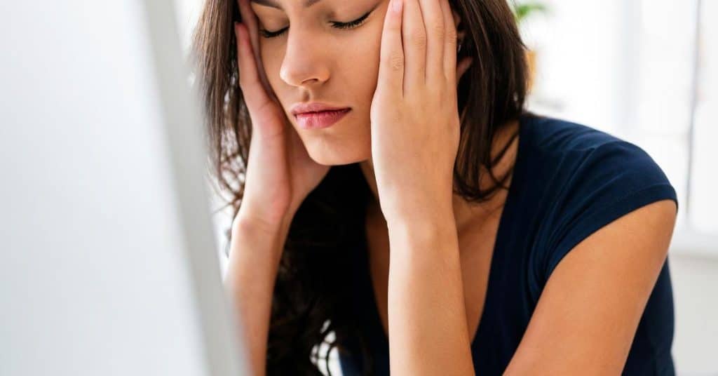 A person closes their eyes while holding their temples
