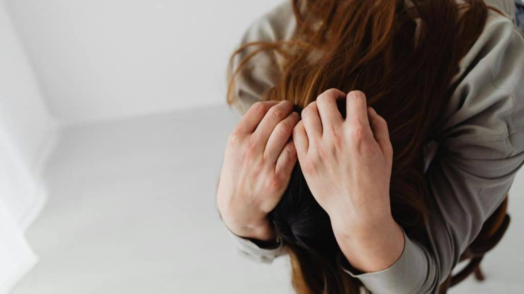 A distressed woman holding her head with both hands.