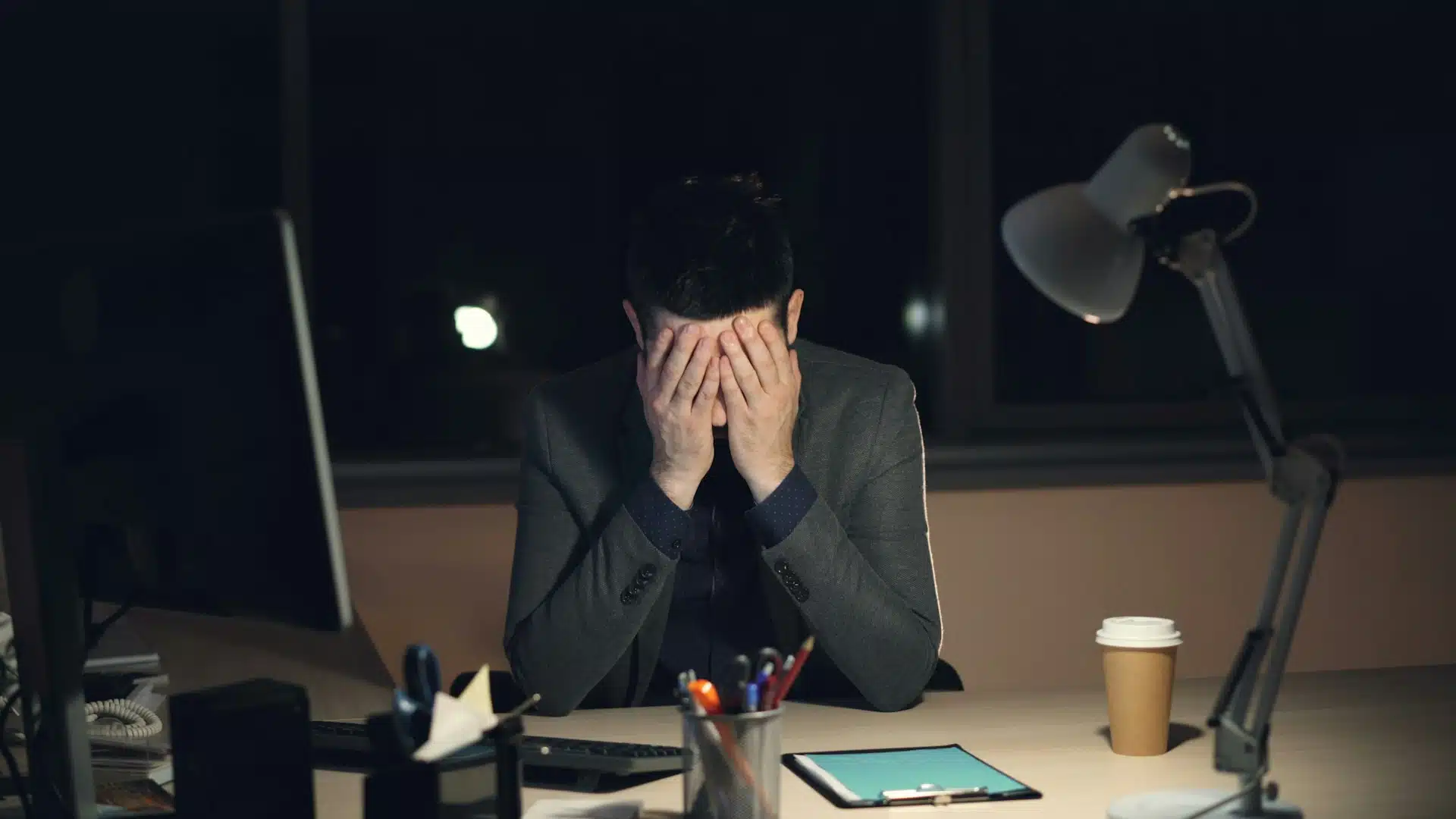 man rubbing forehead at desk